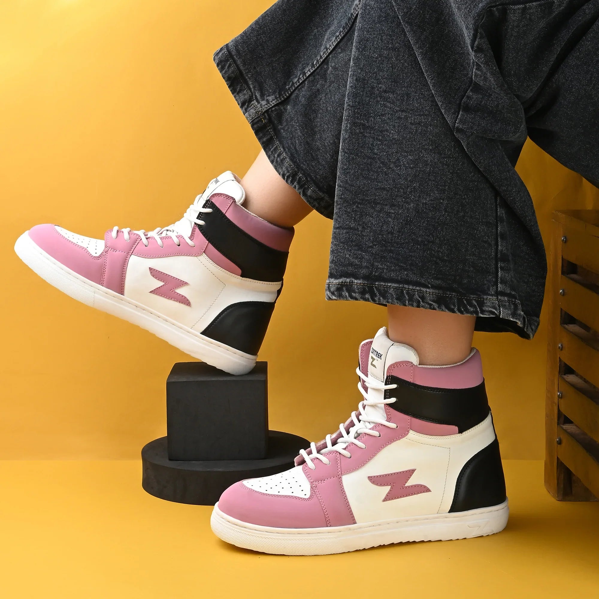 Pink and white sneakers with black accents on a yellow background