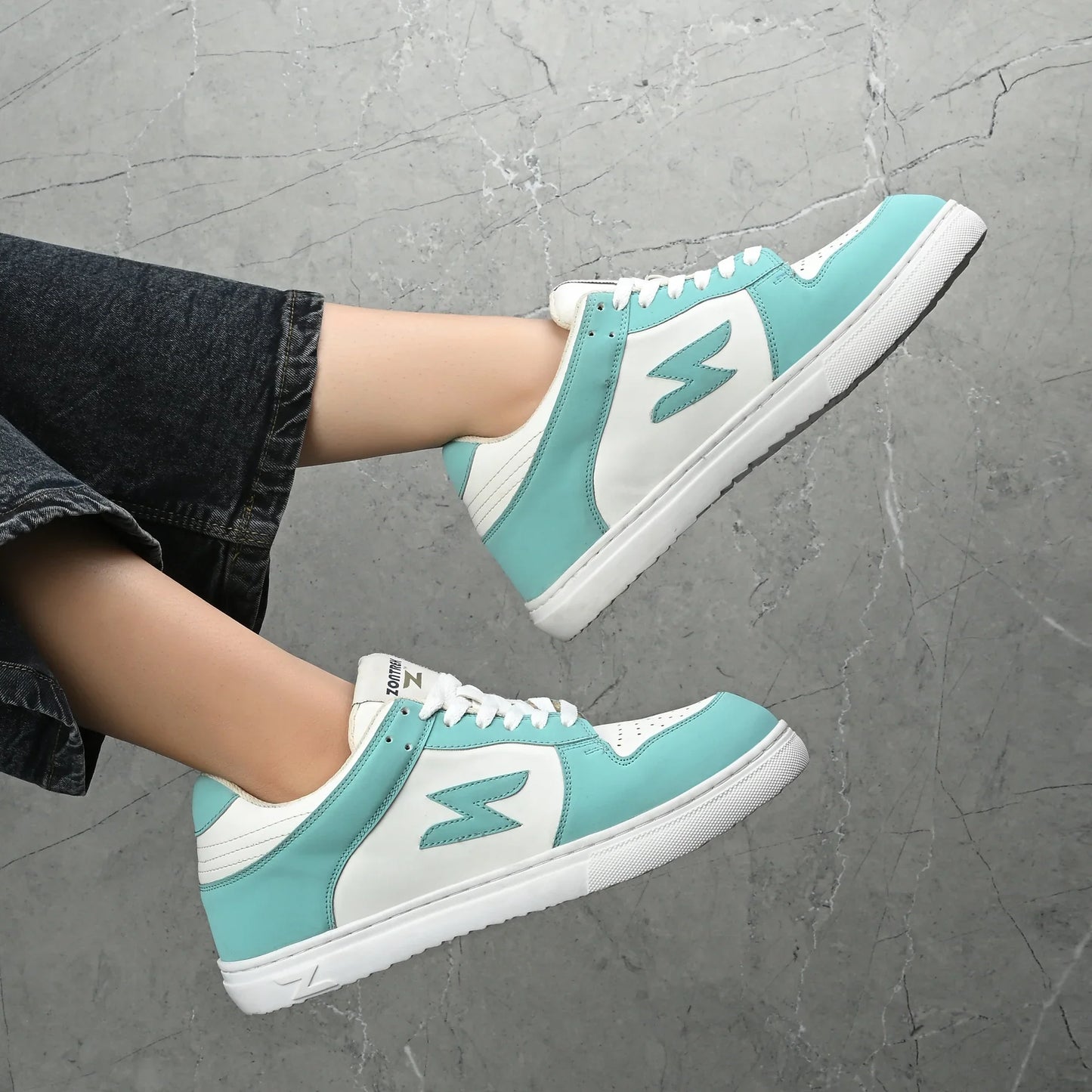 Teal and white sneakers on a gray pavement