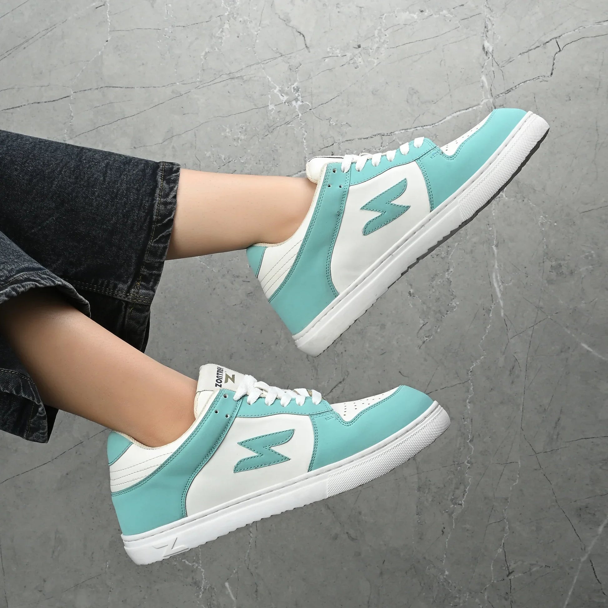 Teal and white sneakers on a gray pavement