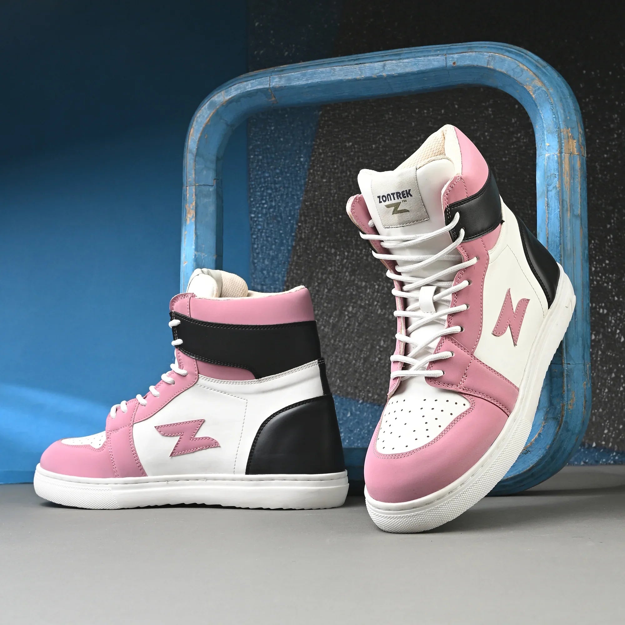 Pink and white high-top sneakers with black accents on a gray surface.